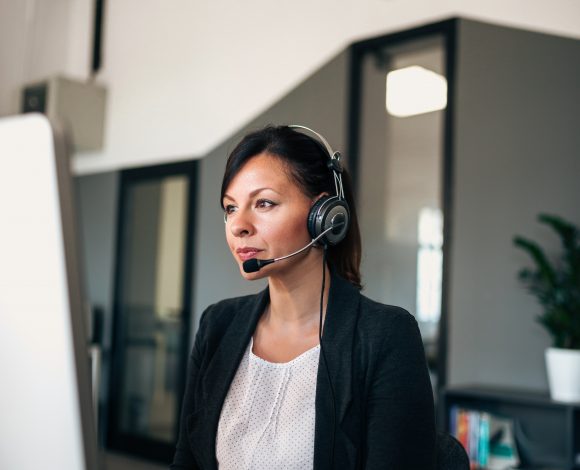 Caucasian female with headset on computer
