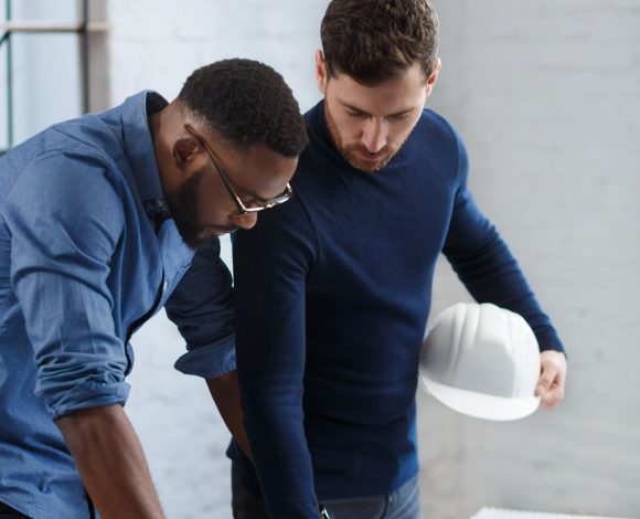 Black male and caucasian male looking at blueprint