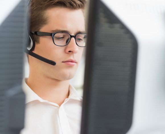 Caucasian male with headset on computer