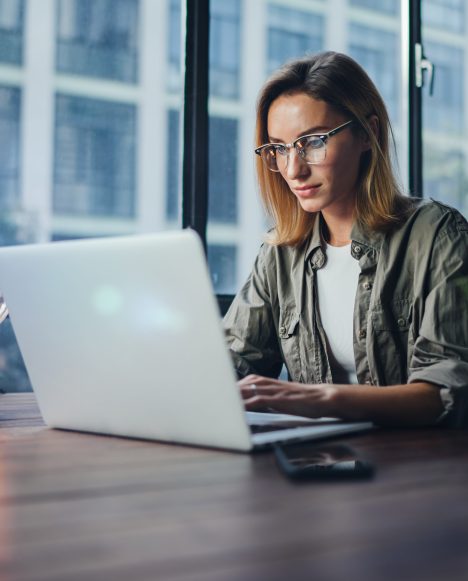 Caucasian female with glasses on laptop