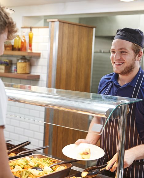 Teenage Students Being Served Meal In School Cafeteria