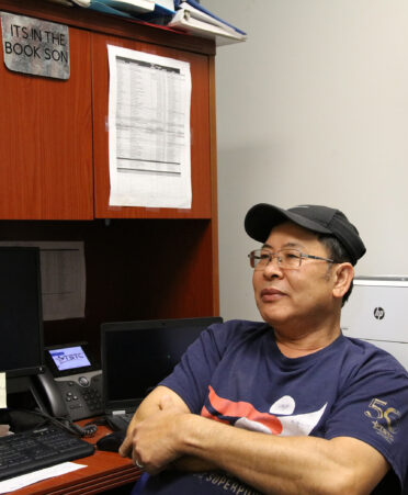 TSTC HVAC Technology instructor Dien Nguyen explains his catchphrase, “It’s in the book, son,” which his students immortalized on a sign for his office, above left.