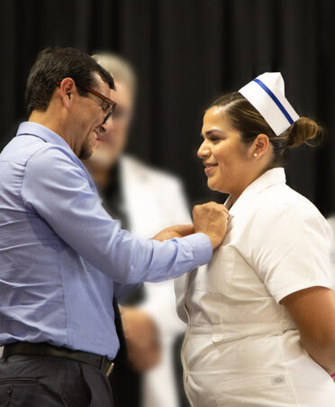TSTC Vocational Nursing graduate Aaron Sotelo has a pin placed on her TSTC Nursing uniform by her father, Victor Sotelo, that signifies her as a newly graduated vocational nurse at the recent TSTC Vocational Nursing pinning ceremony.