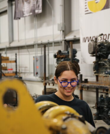 Alyssa stands behind an engine.