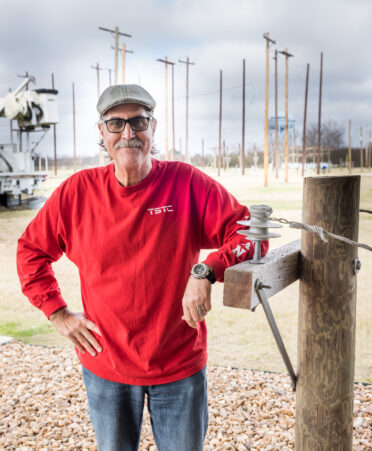 Ronald Jones stands next to some of the Electrical Lineworker and Management Technology program’s electrical equipment, with more in the background.