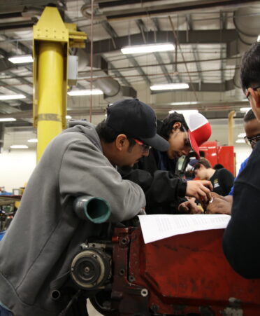 Davis Rios (left) stands with classmates around an engine.