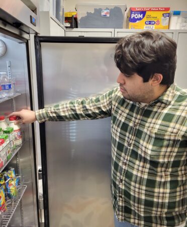 TSTC student Armando Mantano grabs some milk from a freezer at the Fort Bend County campus food pantry.