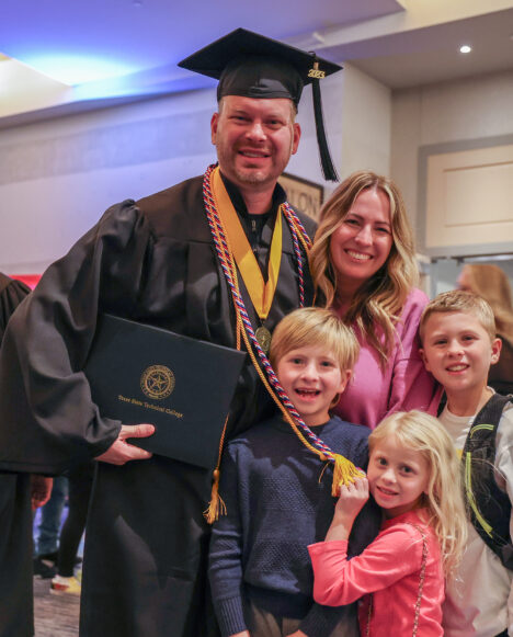 A TSTC graduate is happily surrounded by his wife and three children after the Fall 2023 ceremony.