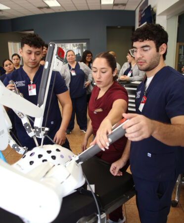 TSTC Surgical Technology students Miguel Flores (left) and Rene Arce (right) observe Brianna Alvarado (center), a clinical representative for Intuitive Surgical Inc., show how to properly manipulate a robotic arm on the da Vinci Xi surgical system during a recent one-day training session at TSTC’s Harlingen campus.
