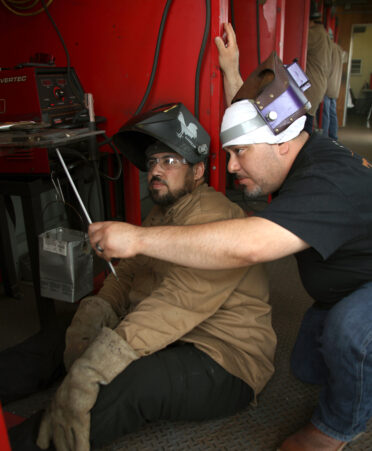 Pedro Garcia (left), a TSTC Workforce Training and Continuing Education Maritime Welding student, listens to an explanation of a root pass in the 4G overhead groove weld position from Samuel Grimaldo, a TSTC Workforce Training Welding instructor, during a recent lab session.