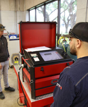 TSTC Welding Technology student Ezequiel Garza (right) monitors the parameters on an orbital tube welding machine that welds thin-walled stainless steel tubing while classmate Angel Castro observes the process during a recent lab session.