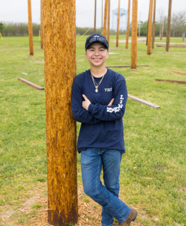 Kelly Gomez leans against an electrical pole used for training.