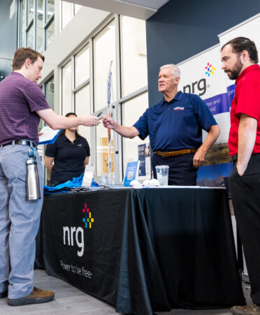 A student shakes hands across a table with an employer at Fort Bend County campus' job fair.