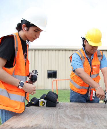 Rio Hondo High School dual enrollment students Bryan Rodriguez (left) and Julio Casas use a battery-operated drill to apply screws to a sheet of plywood that will be used for the subflooring of a trainer building during a recent lab session at TSTC’s Harlingen campus.