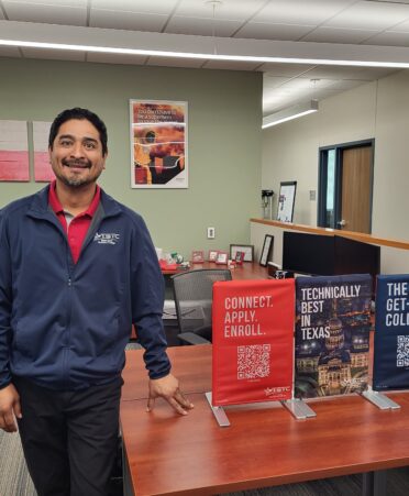 Jesus Ramirez stands next to some recruiting material.