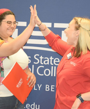Adrianna Herrera Sauceda (left) receives a high-five from Rachel Lantrip, TSTC’s lead recruiter in West Texas, during the National CTE Letter of Intent Signing Day in Abilene on Thursday, April 20. Sauceda signed to study Digital Media Design.