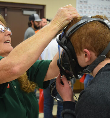 Teresa Purcell (left), a TSTC Occupational Safety and Environmental Compliance instructor in Abilene, helps a Springtown High School senior try on a gas mask during an open house event at TSTC’s Breckenridge campus.