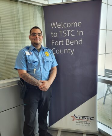 Kolby Risner stands next to a sign welcoming people to TSTC