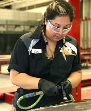 TSTC Auto Collision and Management Technology student Stephanie Luna removes rust from the hood of a 1997 Chevrolet Silverado pickup truck during a recent lab session.