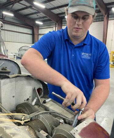 TSTC Aircraft Airframe Technology student Matthew Stokes uses a socket wrench to remove the cowling from a Cessna aircraft engine during a recent lab session.