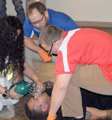 TSTC Emergency Medical Services instructors Tim Scalley (top center) and Steven McCaslin (right) watch as a high school student helps Daniel Aguirre, a Welding Technology instructor at TSTC’s Brownwood campus, breathe during a mock emergency scenario during Allied Health Day at the Brownwood campus.