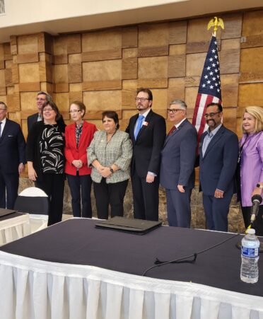 Fort Bend County college leaders stand behind panel desks with American flag in background