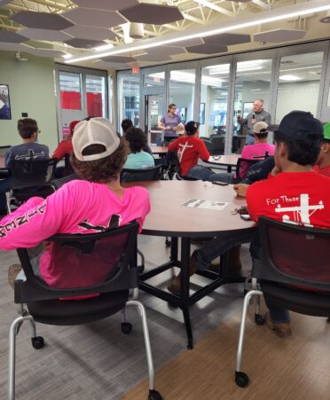 Students sit in chairs listening to representatives.