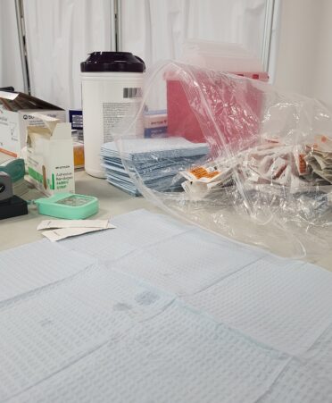 Medical supplies lay on a white table with a white curtain in the background