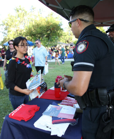 TSTC police officer Alfredo Elizondo (right) talks with Mercedes resident Faythe Pacheco while offering some free school supplies during the recent National Night Out event in Harlingen.
