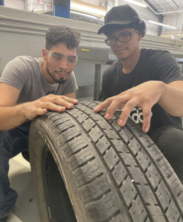 Two men in tshirts looking at a tire