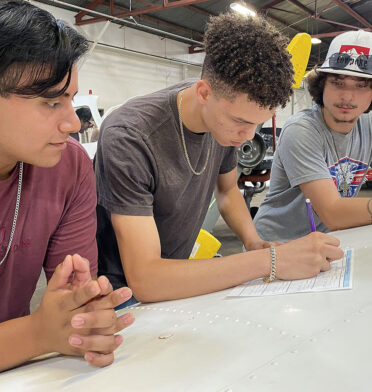 Three men standing looking at piece of paper