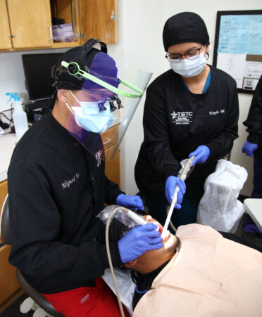 TSTC Dental Hygiene students Miguel Delgado (left) and Kayla Montoya (right) practice cleaning teeth on fellow student Oscar Alonso.