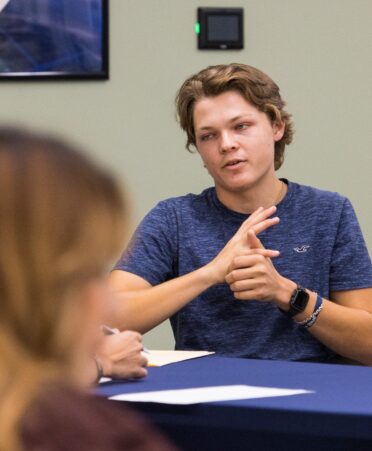 Man wearing blue shirt talks with someone off camera