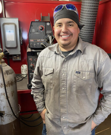 A man standing in front of a red wall with machines on a table