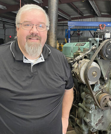 Man in black shirt standing in front of engine