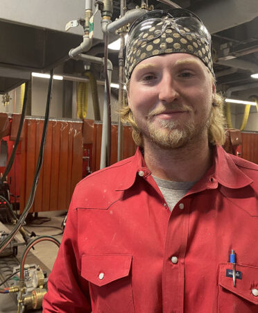 Man in red shirt standing in welding shop