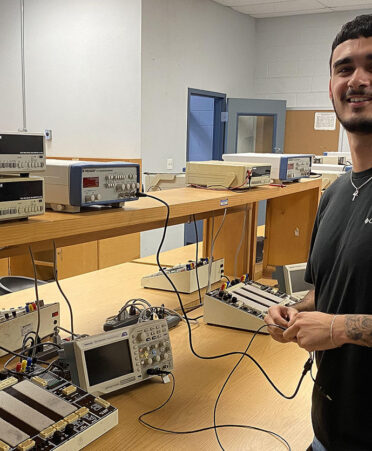 Man in black shirt standing next to electrical equipment