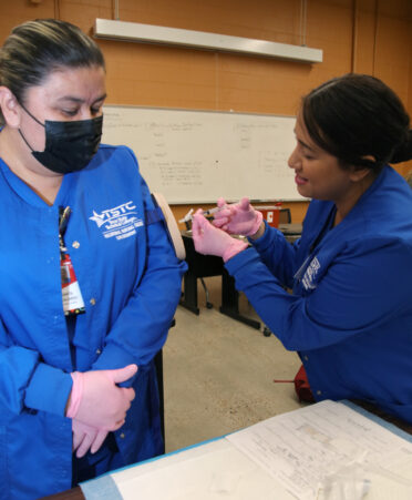 TSTC Vocational Nursing student Cassandra Garcia (right) practices injecting insulin into a practice pad on the arm of fellow classmate Juanita Guajardo during a recent lab session.