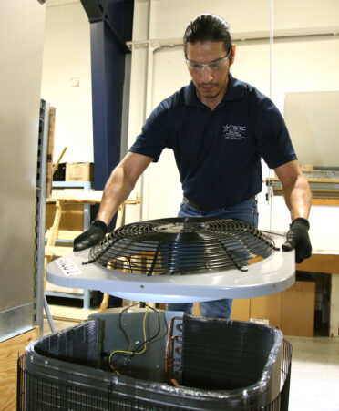 TSTC HVAC Technology student Valentin Lopez removes a condenser fan from an HVAC unit to clean the coils for improved efficiency during a recent lab session.