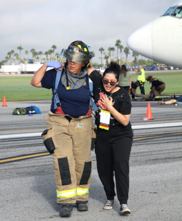 TSTC Surgical Technology student Alexandria Benavidez (right), acting as an injured patient, is helped by Harlingen firefighter Lilliana Nacianceno during an emergency drill on Oct. 12 at Valley International Airport.