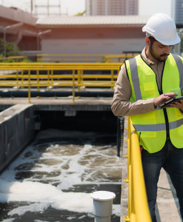 Man in safety vest at water plant reviewing document