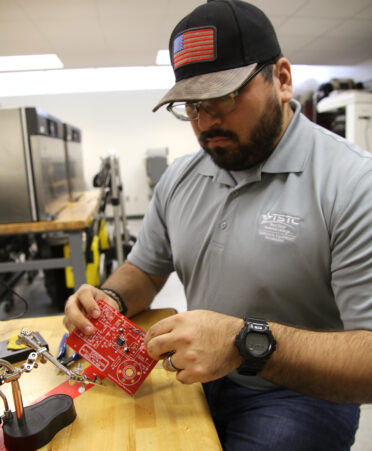 Javier Escobar Jr., a TSTC Biomedical Equipment Technology student, attaches a capacitor chip to an FM radio kit during a lab session.