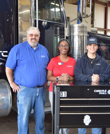 four people standing in front of a diesel truck