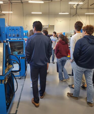 People walk away from the camera looking at blue equipment on their left.