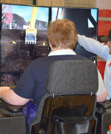 man in blue shirt next to teenager in tshirt on a simulator