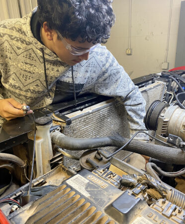 man in gray jacket working on a car engine