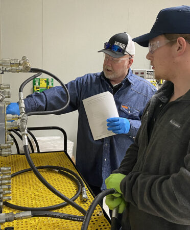 Two men wearing hats working on a lab project