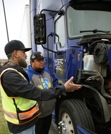 Juan Silguero (left), a TSTC commercial driver’s license instructor, explains how to use proper coolant on a commercial vehicle to Estevan Rivera, a student in TSTC’s Professional Driving Academy, during a recent class session.