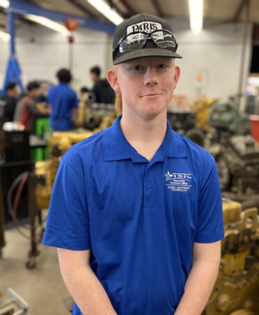 man in blue shirt standing in diesel shop