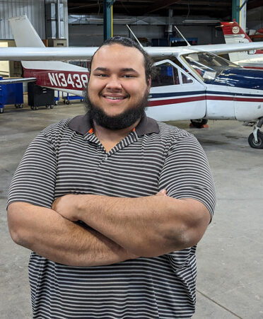 man in striped shirt standing in front of airplanes